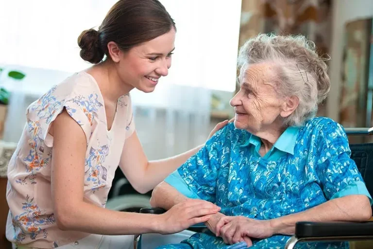 A caregiver and an older woman smiling together at home